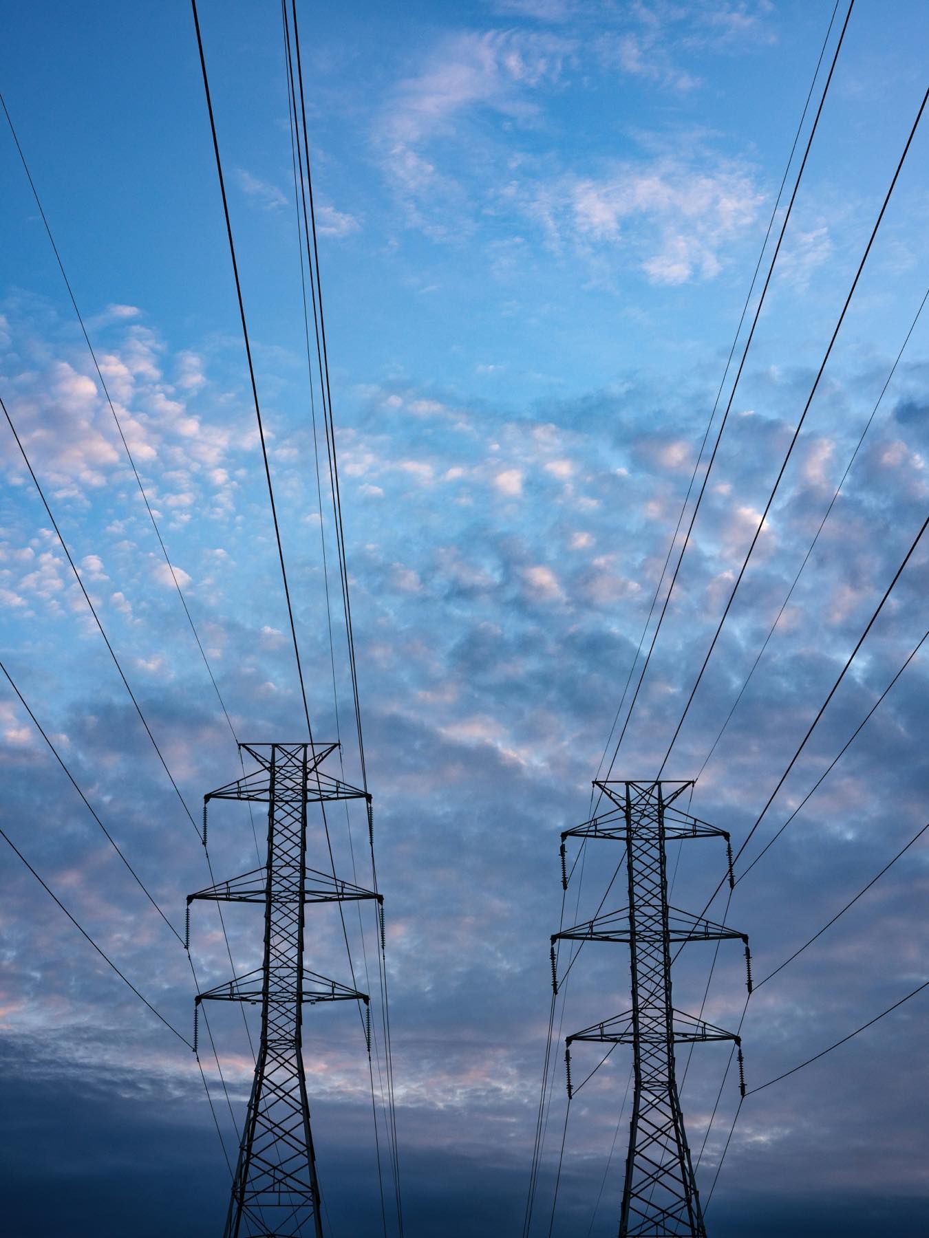 Torres de transporte de energia e condutores ao entardecer
